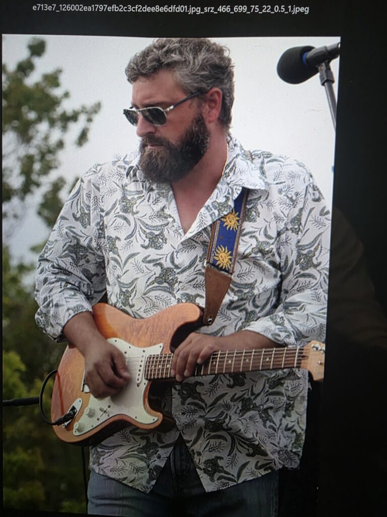 Heath Ledet playing electric guitar during an outdoor live performance