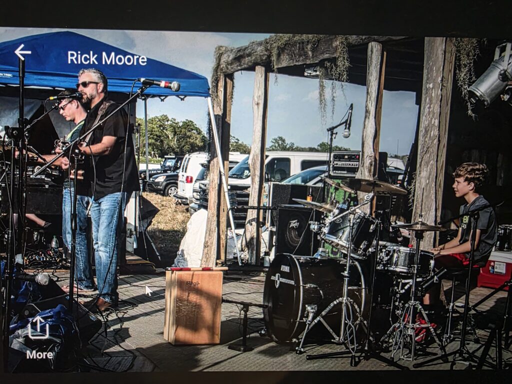 Heath Ledet performing live with guitar alongside other musicians on stage